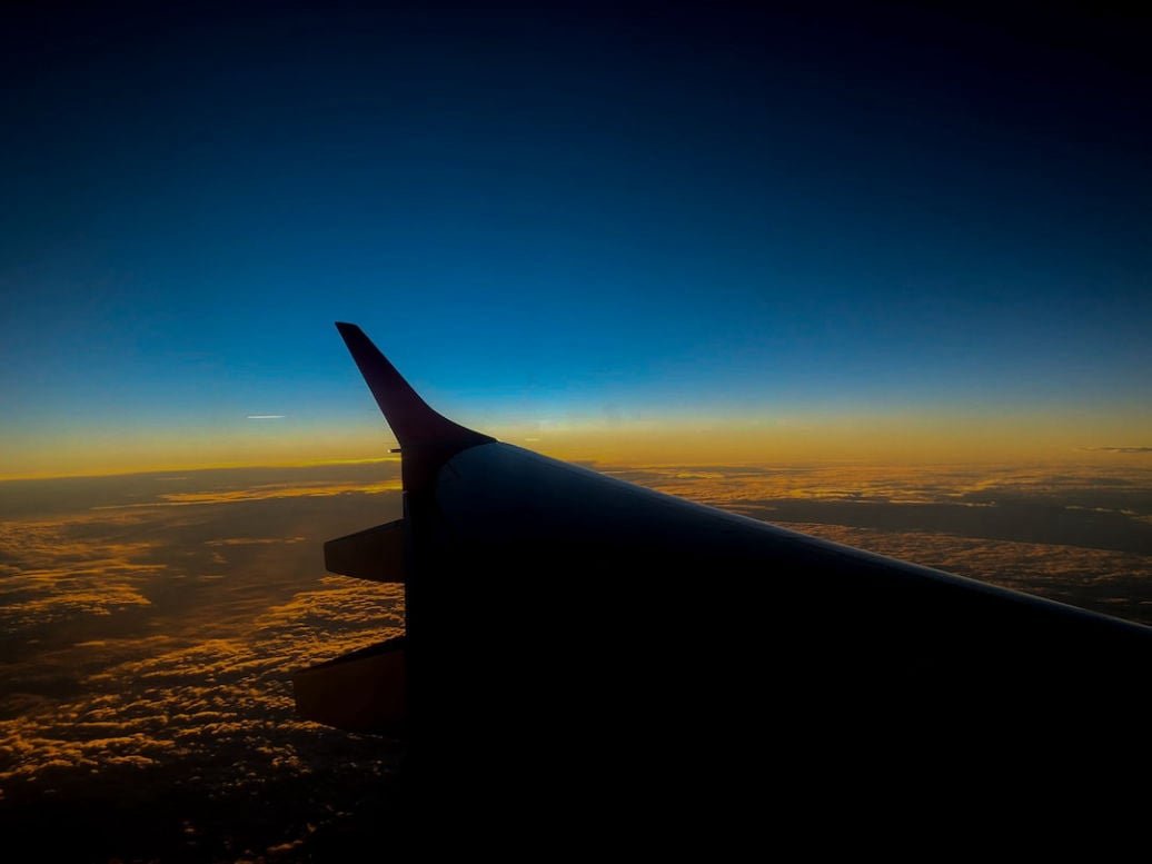 Airplane wing seen from a passenger window at sunset